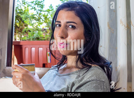 Schöne junge Frau sitzt am Fenster in heißes Getränk Stockfoto