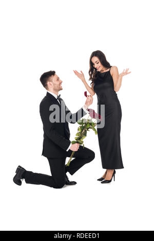 Glückliche Menschen mit roten Rosen geben Vorschlag ring in Feld aufgeregt zu Mädchen, isoliert auf weißem Stockfoto