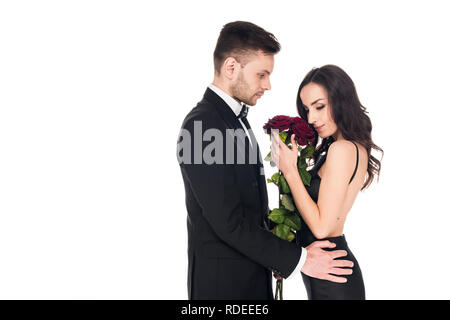 Ausschreibung Paar in schwarzer Kleidung mit roten Rosen am Valentinstag posiert, isoliert auf weißem Stockfoto