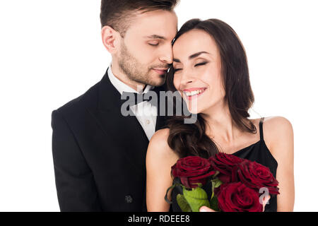 Gerne fröhliche Paar in schwarzer Kleidung mit roten Rosen am Valentinstag posiert, isoliert auf weißem Stockfoto