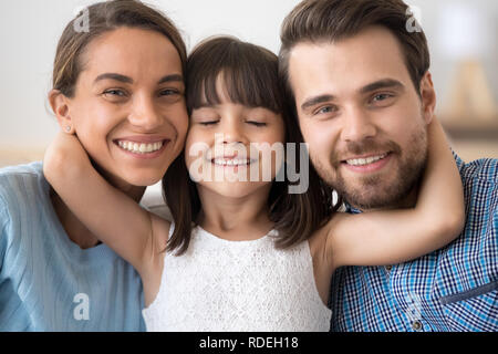 Süße kleine Tochter umarmen Eltern Mama und Papa, headshot por Stockfoto