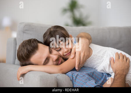 Gerne Vater umarmt niedliche Kind zusammen ruhen auf komfortable Stockfoto