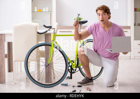 Der Mensch seinem gebrochenen Fahrrad reparieren Stockfoto