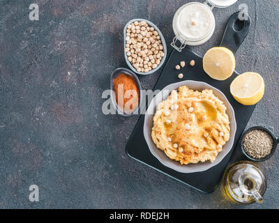 Hausgemachte hummus in grau Schüssel und Zutaten. Traditionelle orientalische Vorspeise Hummus auf dunklem Hintergrund - gesunde Vegane einfügen Snack. Vegetarische Ernährung, Ernährung Protein Food Konzept. Kopieren Sie Platz. Stockfoto