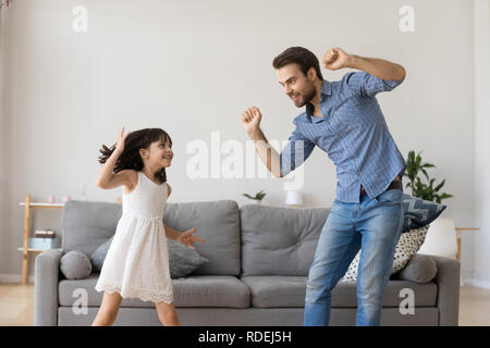 Gerne Vater und Tochter lachen Tanzen im Wohnzimmer. Stockfoto