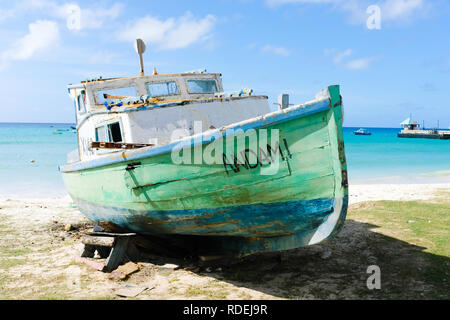 Ein hölzernes Fischerboot in Grün und Blau die Farbe blättert von den Wänden, das bessere Tage gesehen hat, wird auf einem Strand in der Karibik erwarten Reparaturen, die vielleicht doch niemals kommen Stockfoto