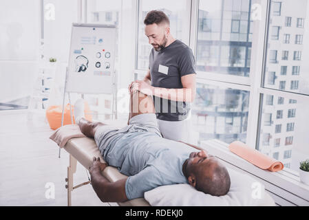 Professionellen Praktiker tun Rehabilitation Massage auf Knie Stockfoto