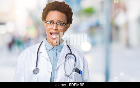 Junge afrikanische amerikanische Ärztin Frau mit medizinischen Mantel über isolierte Hintergrund im Schock Gesicht, schaut skeptisch und sarkastisch, mit offenen überrascht Stockfoto