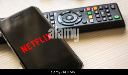 Rom, Italien, 12. Januar 2019; Handy mit dem Netflix logo Bildschirm mit einer TV-Fernbedienung im Hintergrund Stockfoto