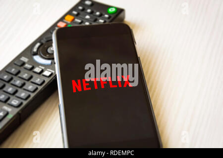 Rom, Italien, 12. Januar 2019; Handy mit dem Netflix logo Bildschirm mit einer TV-Fernbedienung im Hintergrund Stockfoto