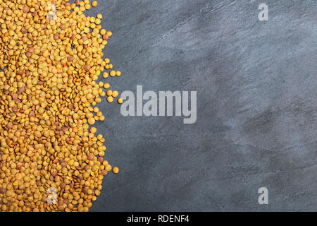 Roh Linsen auf Schwarz Stein Hintergrund. Gesunde vegetarische Essen Konzept. Superfoods. Ansicht von oben, kopieren. Linsen sind reich an komplexen Kohlenhydraten, f Stockfoto