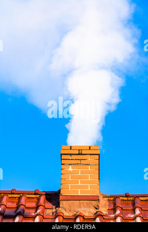 Modernes Haus mit Schornstein rauchen, Luftverschmutzung und Smog in Winter, ökologische Themen Stockfoto