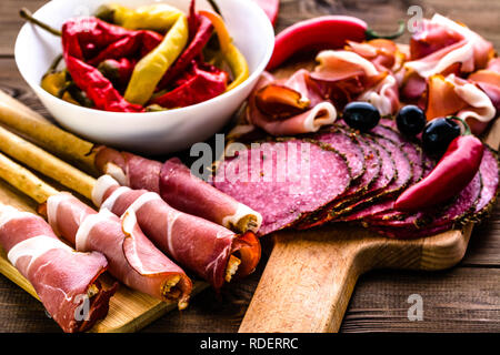 Peperoni salami Scheiben und Brot mit Schinken, italienische Antipasti, essen Platte mit Fleisch, kalte Vorspeisen auf hölzernen Tisch Stockfoto