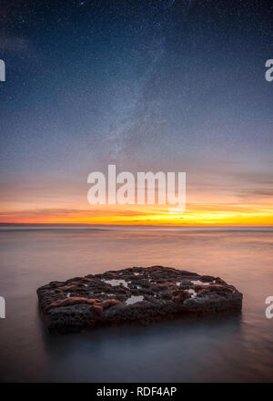 Lange Belichtung auf einem Felsen im Meer mit Sonne im Abstand der Entdeckung der Milchstraße Stockfoto