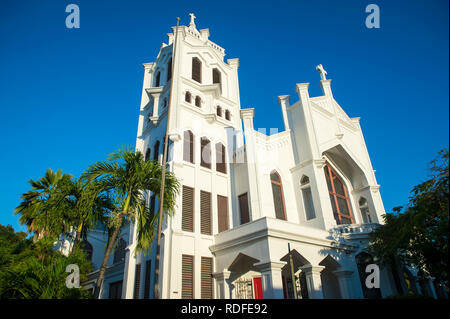 Helle malerischen Blick auf St. Paul's Episcopal Church (erbaut 1919) in einfachen weißen Beton mit Palmen in Key West, Florida, USA Stockfoto
