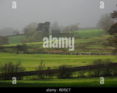 Regentropfen streuen das Licht mit grauem Himmel über alte Scheune inmitten grüner Felder an einem regnerischen Tag in ländlichen Cumbria, England, Großbritannien Stockfoto