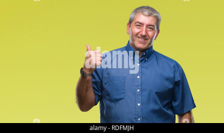 Gut aussehender älterer Mann über isolierte Hintergrund lächelnd mit glücklichen Gesicht und zeigt auf die Seite mit dem Daumen nach oben. Stockfoto