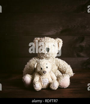 Zwei alte braune weiche Teddybären sitzen auf einem hölzernen Oberfläche, vintage Toning Stockfoto