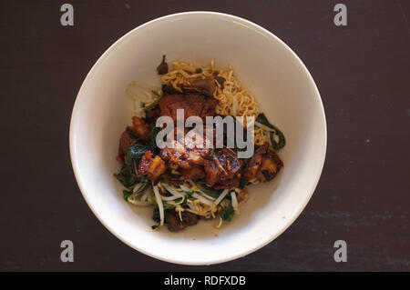 Ei Nudeln mit knusprigen Schweinefleisch und Morning Glory in der Schüssel auf dem Tisch, Essen in Thailand Stockfoto