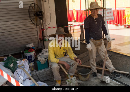 15.03.2018, Singapur, Republik Singapur - Zwei Chinesische Wanderarbeiter sind eine Pause von der Arbeit im Zentrum der Stadt. Stockfoto