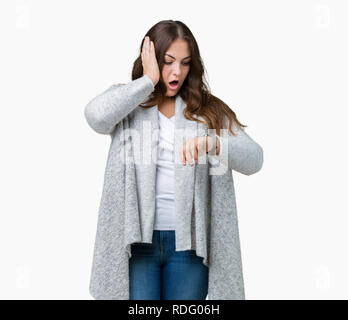 Schöne Übergrößen junge Frau tragen Winter Jacke über isolierte Hintergrund ein Blick auf die Uhr Zeit Sorgen, Angst, sich spät Stockfoto