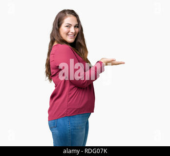 Schöne Übergrößen junge Frau über isolierte Hintergrund verweist auf die Seite mit der Hand und öffnen Sie Palm, präsentiert ad lächelte glücklich und zuversichtlich Stockfoto