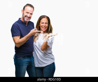 Mittleres Alter spanischer casual Paar über isolierte Hintergrund erstaunt und lächelt in die Kamera während der Präsentation mit Hand und zeigte mit dem Finger. Stockfoto
