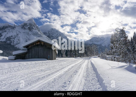 Winter Berglandschaft mit präparierten Loipe und schneebedeckte Bäume entlang der Straße, Ehrwald, Tirol, Alpen, Österreich. Sonnigen Wintertag. Stockfoto