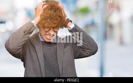 Junge gut aussehender Geschäftsmann mit Afro Brille Kopfschmerzen leiden, verzweifelte und betonte, weil Schmerz und Migräne. Hände auf den Kopf. Stockfoto