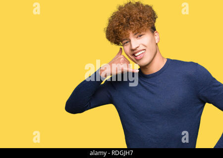 Junger stattlicher Mann mit afro Haar lächelnd tun Telefon Geste mit der Hand und der Finger wie im Gespräch am Telefon. Verbreitung von Konzepten. Stockfoto