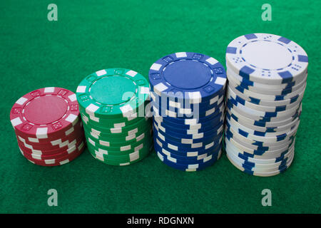 Stapel von Poker chips einschließlich Rot, Weiß, Grün und Blau auf einen grünen Hintergrund. Perspektive betrachten. Stockfoto