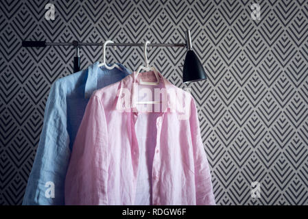Rosa und Blaue Hemden auf Kleiderbügeln, auf modernen Hintergrund. Stockfoto