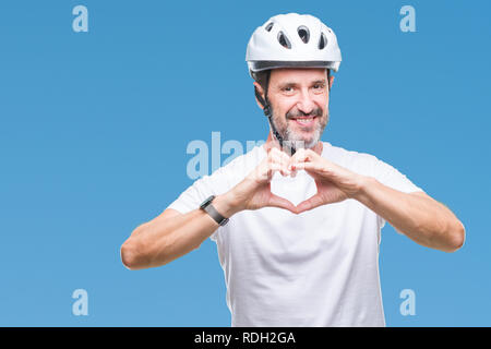 Mittleres Alter senior hoary Radfahrer Mann mit Fahrrad Sicherheit helment isoliert Hintergrund lächelnd in Liebe mit Herz und Formen mit den Händen. Romantische Stunden Stockfoto
