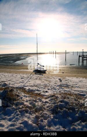 Bucht im Wattenmeer mit einem Segelboot, verschneite Strand auf der ostfriesischen Nordseeinsel Spiekeroog, Niedersachsen Stockfoto