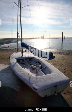 Bucht im Wattenmeer mit einem Segelboot, verschneite Strand auf der ostfriesischen Nordseeinsel Spiekeroog, Niedersachsen Stockfoto