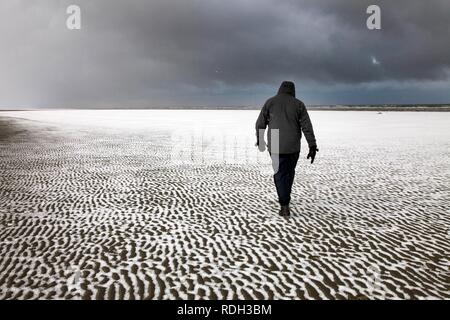 Person zu Fuß entlang der verschneiten Strand auf der ostfriesischen Nordseeinsel Spiekeroog, Niedersachsen Stockfoto