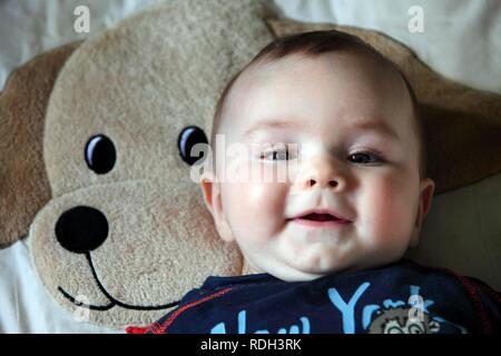 Little Boy, 6 Monate, lag auf dem Rücken auf einer Decke im Schlafzimmer seiner Kinder, lächelnd Stockfoto