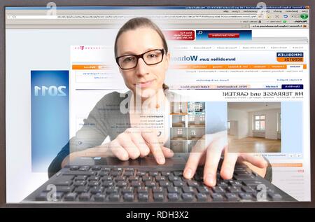 Junge Frau an einem Computer beim Surfen im Internet, Anzeigen einer Immobilienportal, Immobilienscout24.de Stockfoto