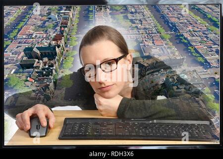 Junge Frau an einem Computer mit Google Street View sitzen, Detailgenauigkeit mit einem Abschnitt der Stadt Amsterdam, Menschen und Stockfoto