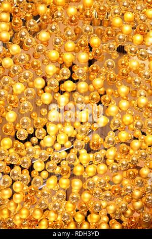 Weihnachtsschmuck, viele kleine goldene Weihnachtskugeln bilden eine große Weihnachtskugel hängen im Treppenhaus eines Stockfoto