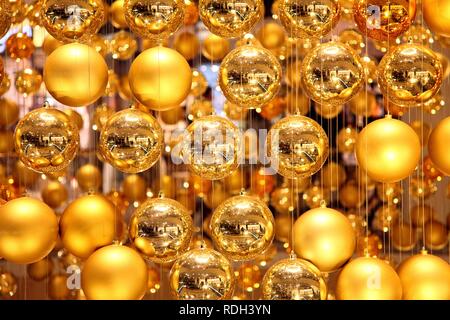 Weihnachtsschmuck, viele kleine goldene Weihnachtskugeln bilden eine große Weihnachtskugel hängen im Treppenhaus eines Stockfoto