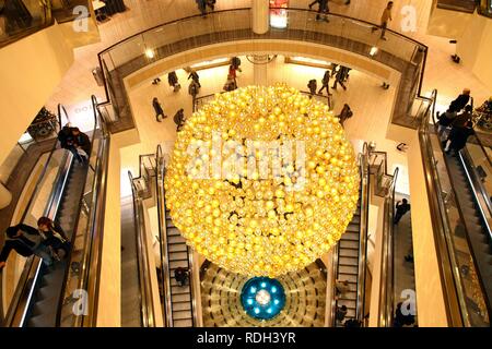 Weihnachtsschmuck, viele kleine goldene Weihnachtskugeln bilden eine große Weihnachtskugel hängen im Treppenhaus eines Stockfoto