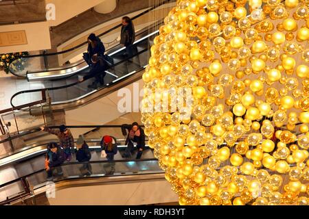 Weihnachtsschmuck, viele kleine goldene Weihnachtskugeln bilden eine große Weihnachtskugel hängen im Treppenhaus eines Stockfoto