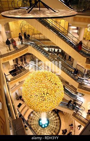 Weihnachtsschmuck, viele kleine goldene Weihnachtskugeln bilden eine große Weihnachtskugel hängen im Treppenhaus eines Stockfoto