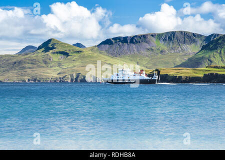 Calmac Fähre auf dem Meer mit den grünen Bergen im Hintergrund - Caledonian MacBrayne Fähren im Hochland von Schottland, Äußere Hebriden Stockfoto