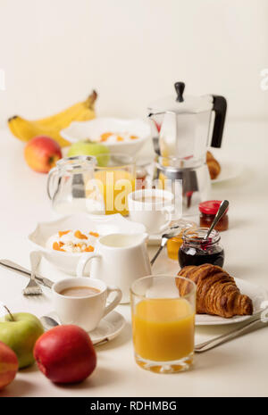Zeit für das Frühstück. Orangensaft und Croissants, Marmelade und Honig. Kaffee mit Sahne oder Milch. Früchte wie Bananen, rote und grüne Äpfel. Ricotta mit Sauerrahm Stockfoto