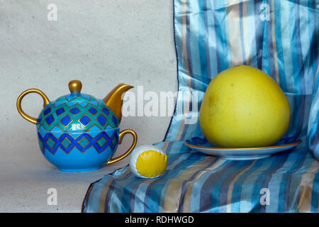 Farbenfrohe still life Foto von verschiedenen Objekten: Teekanne, Platte, Grapefruit, Seidenschal Stockfoto