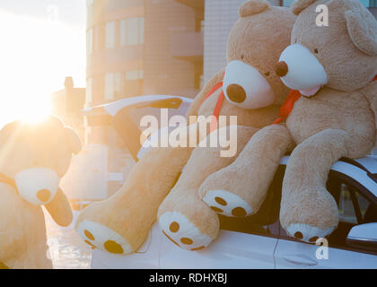 Riesige Teddybären mit roten Bändern saß oben auf der Motorhaube outdoor. Platz für Text. Liebe, Valentines Tag Konzept Stockfoto