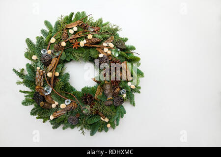 Schöne handgemachte Weihnachten Kranz auf weißem Hintergrund, grüne Zweige mit Tannenzapfen und anderen Dekorationen verziert Fichte Stockfoto