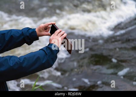 Alter Mann Hände halten ein Telefon. Älterer Mann mit smart phone Aufnahmen im Freien Stockfoto
